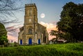 Moon in the sky at sunset behind church clock tower in Corsley, Wiltshire, UK Royalty Free Stock Photo