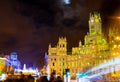 The moon in the sky, under it the city hall of Madrid illuminated with green lights