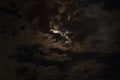 Moon. Slightly cloudy night sky, the moon shining brightly through the clouds.