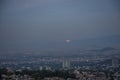 Moon sphere peeking out from behind the mountains over the city