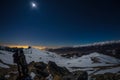 Moon and starry sky, snow on the Alps, fisheye lens. Orion Constellation, Betelgeuse and Sirio. Long exposure blurred two hikers l