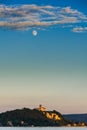 Moon under scattered clouds over a castle on a lake at sunset Royalty Free Stock Photo