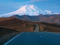 Moonlight on Elbrus mountain. Morning landscape with winding highway to Mount Elbrus under morning sky with full moon. Empty road