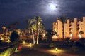 Moonlight illuminating tropical resort with hotel building and palm trees at night