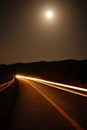 A moonlit road with car trails