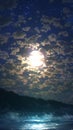 Moonlit sky over tranquil sea, with clouds adding mystical beauty