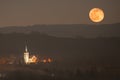 Moonrise over the mountains in the Sudetes, illuminated church in Stary Waliszow