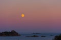 Moonrise over the ocean with cliffs in the foreground Royalty Free Stock Photo