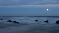 Moonrise over a rocky shore.