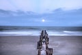 Moonset at Dawn over a dilapidated pier on the beach in Port Royal