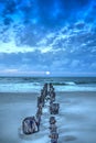 Moonset at Dawn over a dilapidated pier on the beach in Port Royal