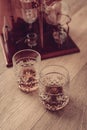 Moonshine still and two glasses with ice and whiskey on wooden background