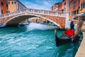 Moored boats and bridge over water canal in Venice, Italy