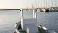 Moored fishing boat is lulled by the water while the sun reflects off the sea early in the morning