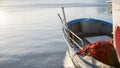 The moored fishing boat is lulled by the water while the sun reflects on the sea early in the morning with the red fishing net in