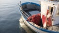 The moored fishing boat is lulled by the water while the sun reflects on the sea early in the morning with the winch of the