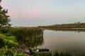 Moored fishing inflatable rubber boat and a fishing rod near the shore of the lake. Royalty Free Stock Photo