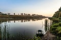 Moored fishing inflatable rubber boat and a fishing rod near the shore of the lake. Summer early morning and sunrise. Royalty Free Stock Photo