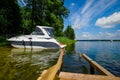 Moored motorboat near old wooden pier on a lakeshore in a sunny summer day Royalty Free Stock Photo