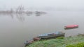Fishing row boats and fisherman`s huts in deep autumn fog. Royalty Free Stock Photo