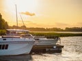 Moored pleasure boat and motorboat near the old wooden pier on the lake in the evening with sunset light on the background Royalty Free Stock Photo