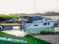 Moored pleasure boat and motorboat near the old wooden pier on the lake in the evening with sunset light on the background Royalty Free Stock Photo