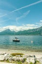 Moored sailboat on lake Garda & shorline with orange and white buoys, at stern of boat