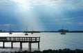 Moored sailboats in calm bay with dramatic clouds sun rays