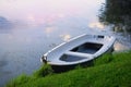 Moored small boat on the shore of a lake, A tranquil water reflects a pink sky Royalty Free Stock Photo