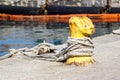 A mooring bollard entwined with a mooring rope. Moored ships at the port quay Royalty Free Stock Photo