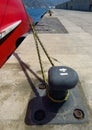 Mooring bollard with heavy duty mooring ropes. Detail of mooring with the rope of the boat in the dock. Noray with red merchant