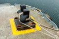 Mooring cable tied to an iron bollard on a concrete dock, boat cable Royalty Free Stock Photo