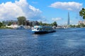 Mooring excursion boat with tourists against the backdrop of houses, towers and a blue sky with clouds. St. Petersburg