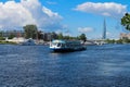 Mooring excursion boat with tourists against the backdrop of houses, towers and a blue sky with clouds. St. Petersburg