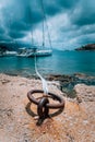 Mooring rope and bollard on sea water and yacht at the background. Dramatic Rainy clouds above mediterranean sea