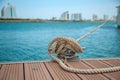 Mooring yacht rope with a knotted end tied around a cleat on a wooden pier Royalty Free Stock Photo