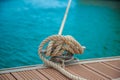 Mooring yacht rope with a knotted end tied around a cleat on a wooden pier Royalty Free Stock Photo