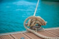 Mooring yacht rope with a knotted end tied around a cleat on a wooden pier Royalty Free Stock Photo