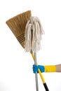 Mop and broom being held by a rubber gloved hand