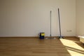 A mop and bucket and a broom stand on a parquet floor in an empty room