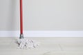 Mop with plastic handle near wall indoors. Space for text Royalty Free Stock Photo