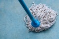 Mop with PVC blue handle standing on cement flooring background closeup to clean hygiene.