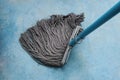 Mop with PVC blue handle standing on cement flooring background closeup to clean hygiene.