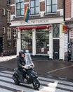 Moped rider driving past a gay bar on Amstel street in Amsterdam