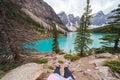 Moraine Lake in Banff National Park on an overcast day, with a woman sitting on the rocks, only feet in sandals showing Royalty Free Stock Photo