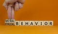 Moral or ethical behavior symbol. Businessman turns cubes, changes words ethical behavior to moral behavior. Beautiful orange