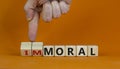 Moral or immoral symbol. Hand turns cubes and changes the word `immoral` to `moral`. Beautiful orange background. Business and Royalty Free Stock Photo