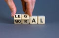 Moral or legal symbol. Businessman hand turns wooden cubes and changes the word `moral` to `legal` on a beautiful grey table,