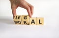 Moral or legal symbol. Businessman turns wooden cubes and changes the word `moral` to `legal` on a beautiful white table, whit