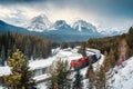 Morants Curve with iconic red cargo train passing through bow valley and rocky mountains in winter at Banff national park Royalty Free Stock Photo